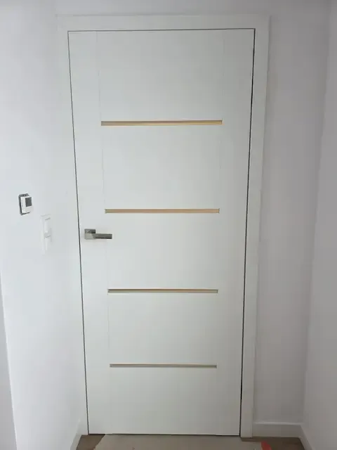 Białe drzwi wewnętrzne ze złotymi listwami