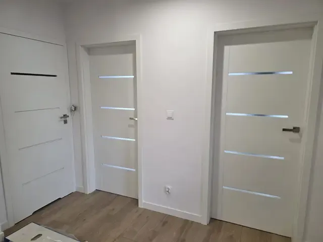 Dwoje białych drzwi wewnętrznych z przeszkleniami po montażu